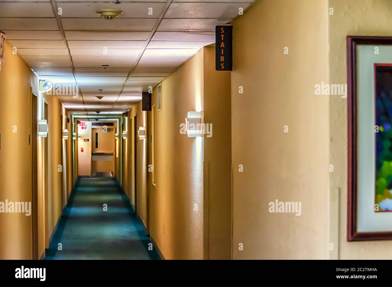 Una vista del largo pasillo del hotel, iluminado por varias luces. Las  señales de salida y escaleras son visibles Fotografía de stock - Alamy