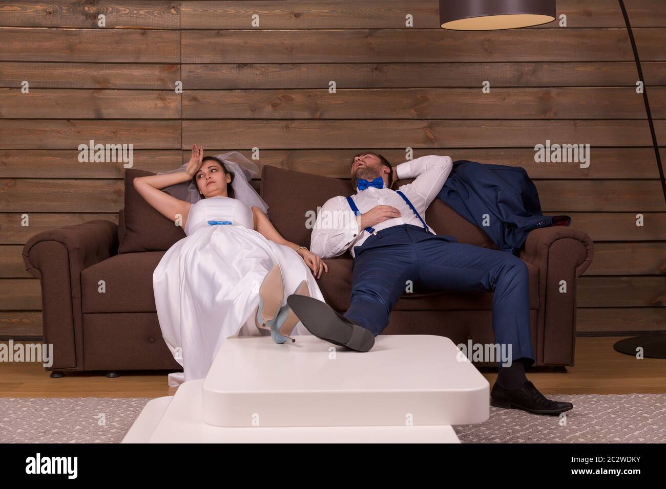 Cansado novio y novia descansar en cama después de la boda, de madera del interior de la habitación a fondo. Foto de stock