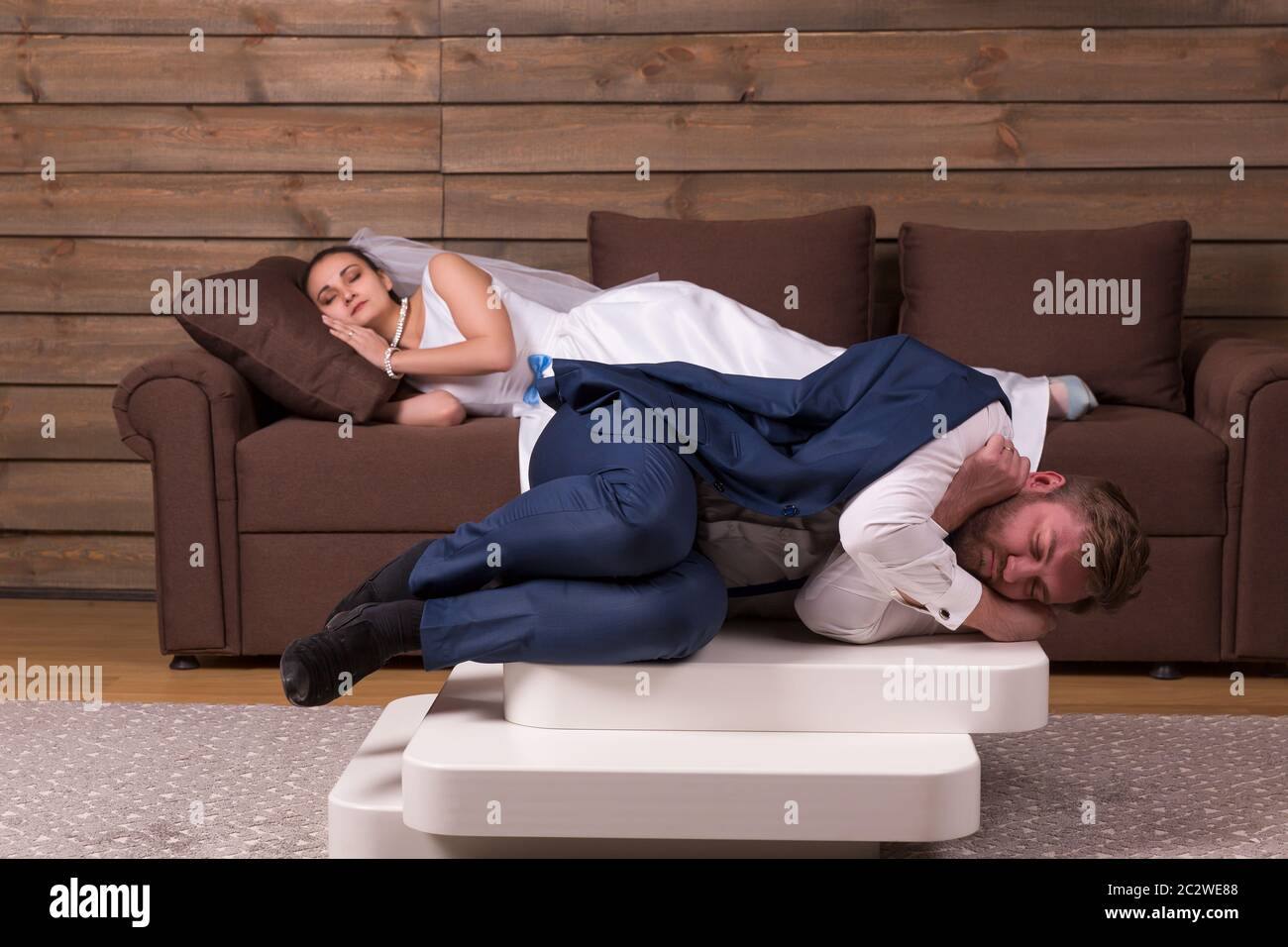 Cansado para el novio y la novia están durmiendo en el sofá después de la celebración de boda Foto de stock