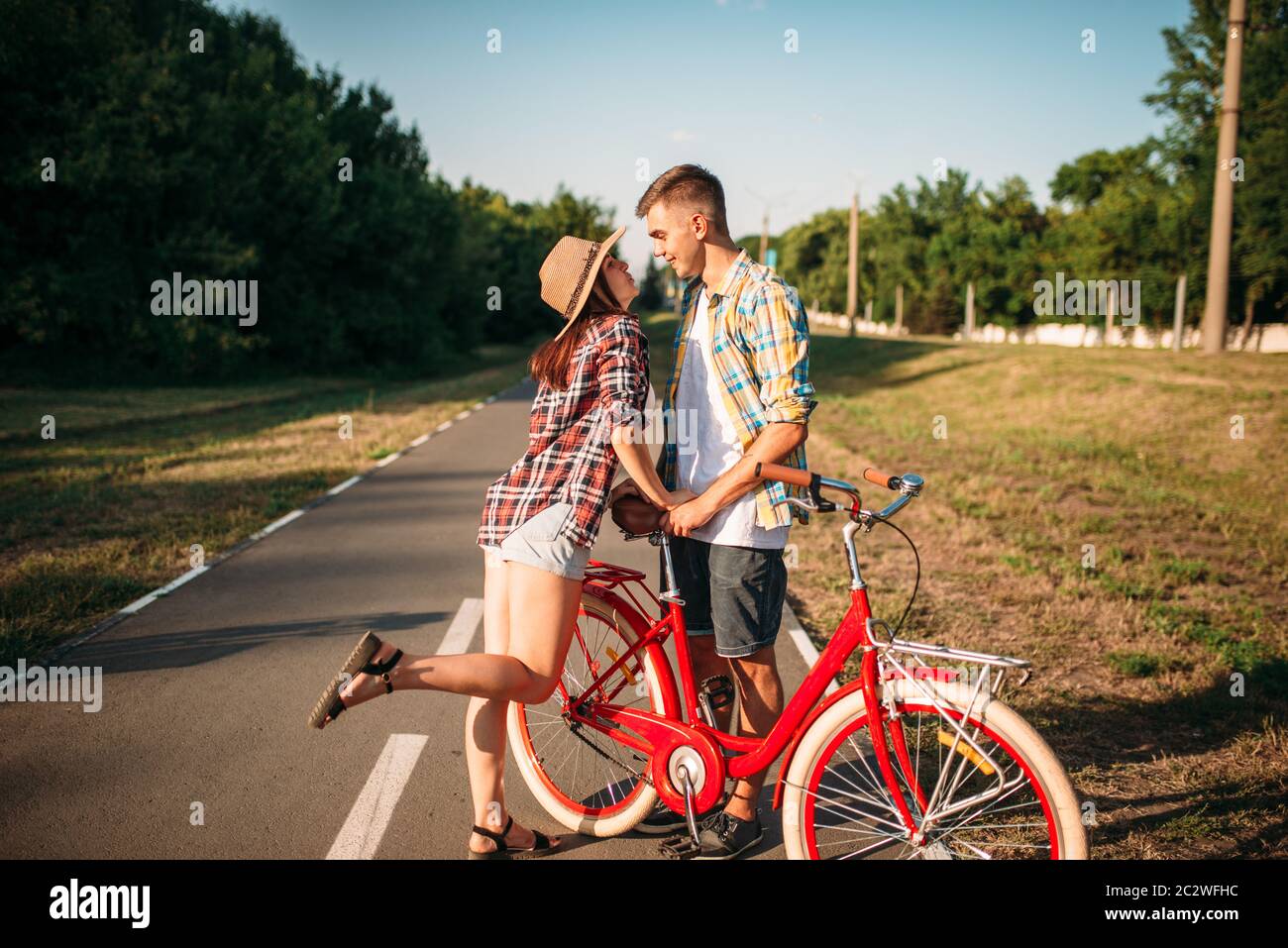 Pareja de amor con bicicleta de época caminando en el parque de verano,  fecha romántica de hombre y mujer. Novio y novia juntos al aire libre,  bicicleta retro Fotografía de stock -