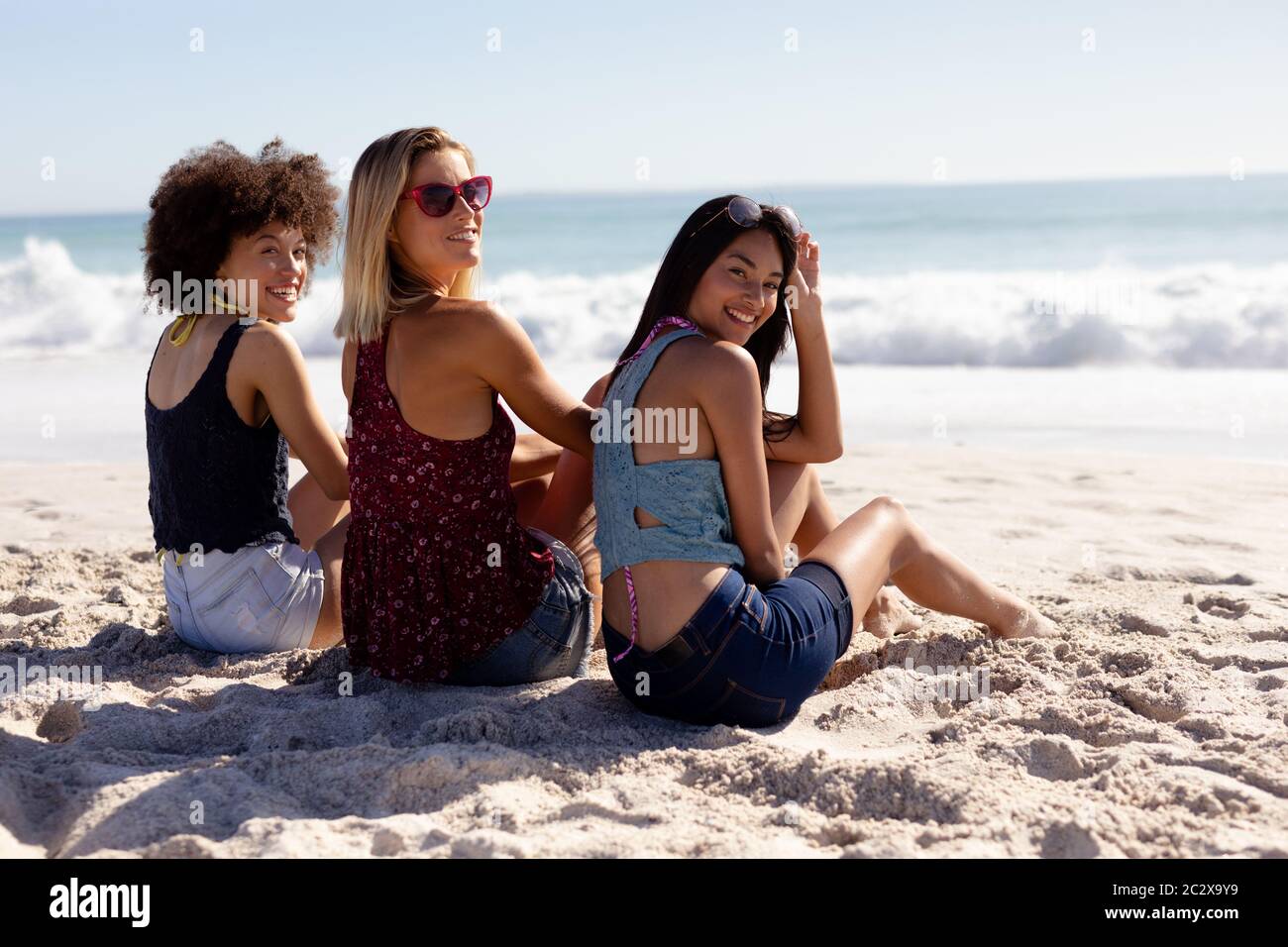 Grupo multiétnico de mujeres sentadas en la playa Foto de stock