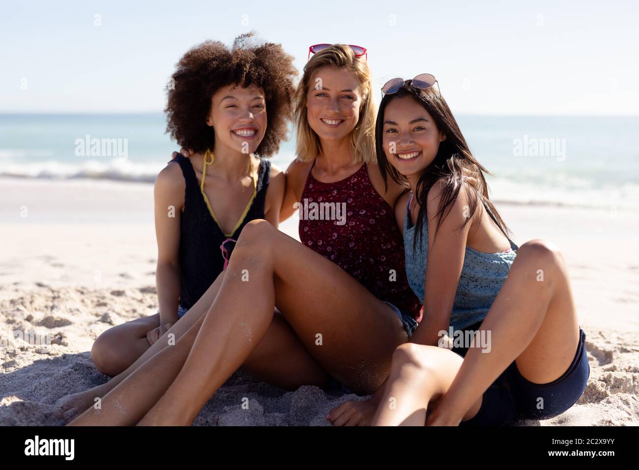 Grupo multiétnico de mujeres sentadas en la playa Foto de stock