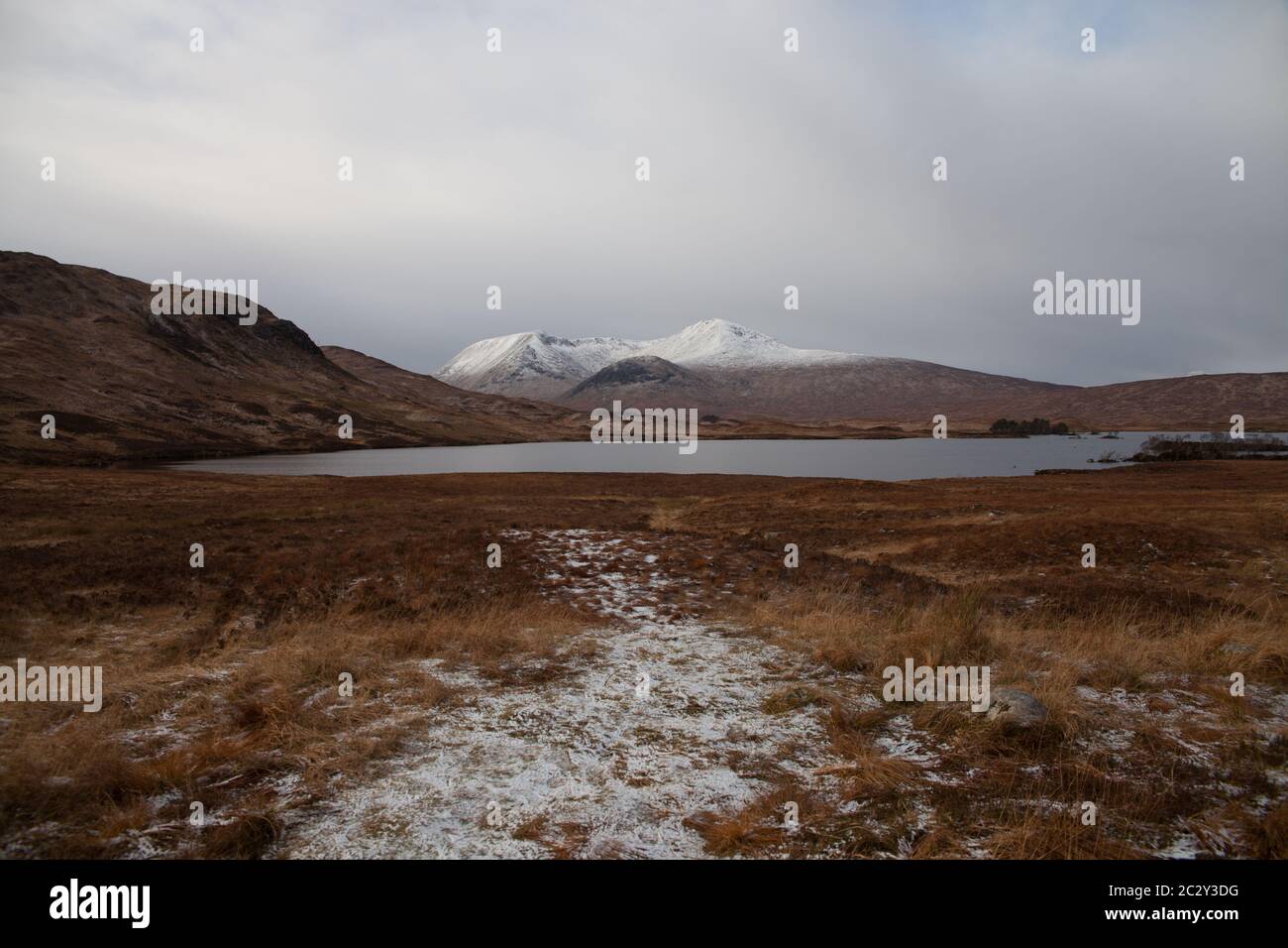 Montañas cubiertas de nieve en la distancia con un lago, Glencoe Escocia Foto de stock