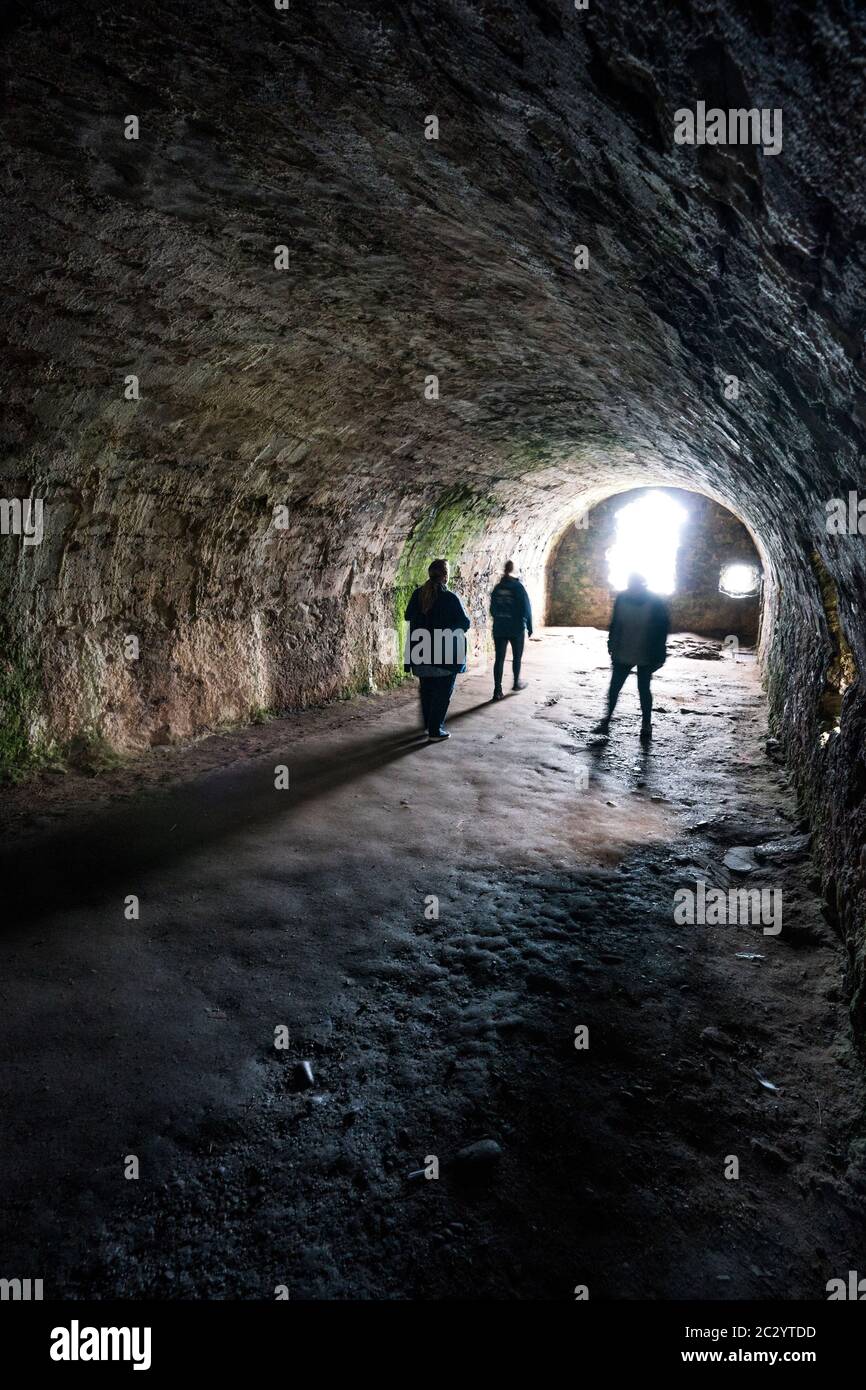 Tres personas se encuentran en la bóveda arqueada de los Whigs, donde 167 Covenanters fueron encarcelados y torturados durante 9 semanas en 1685, Dunnottar, Escocia, Reino Unido, Europa Foto de stock