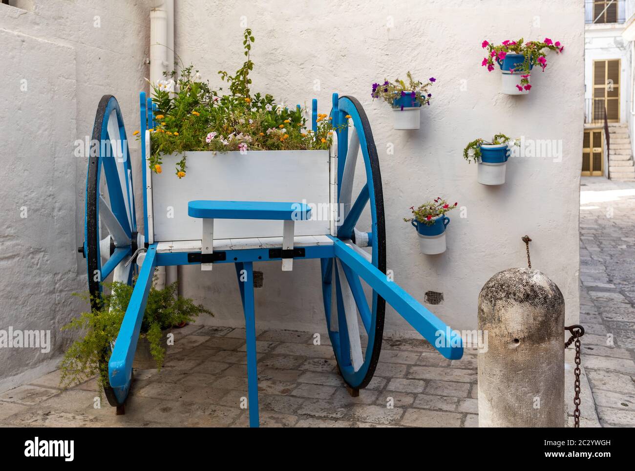 Un coche de madera pintada de blanco y azul decorado con flores en Polignano a Mare. Apulia, Italia Foto de stock