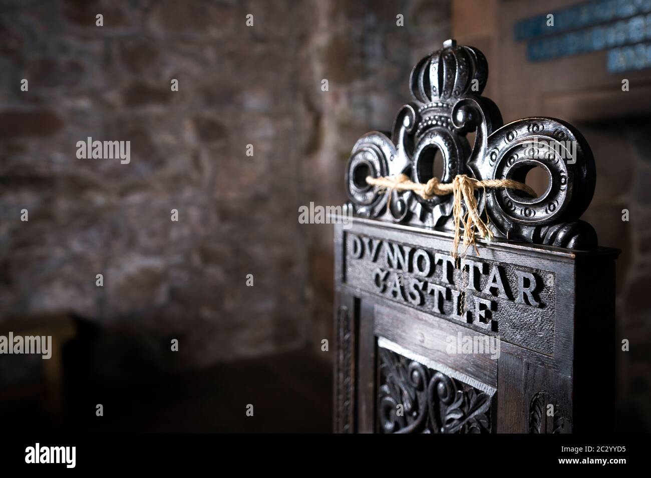 Silla de madera ornamentada con tallas de flores y pergamino y una corona en lo alto del trono con letras Dunnottar Castle, Escocia, Reino Unido Foto de stock