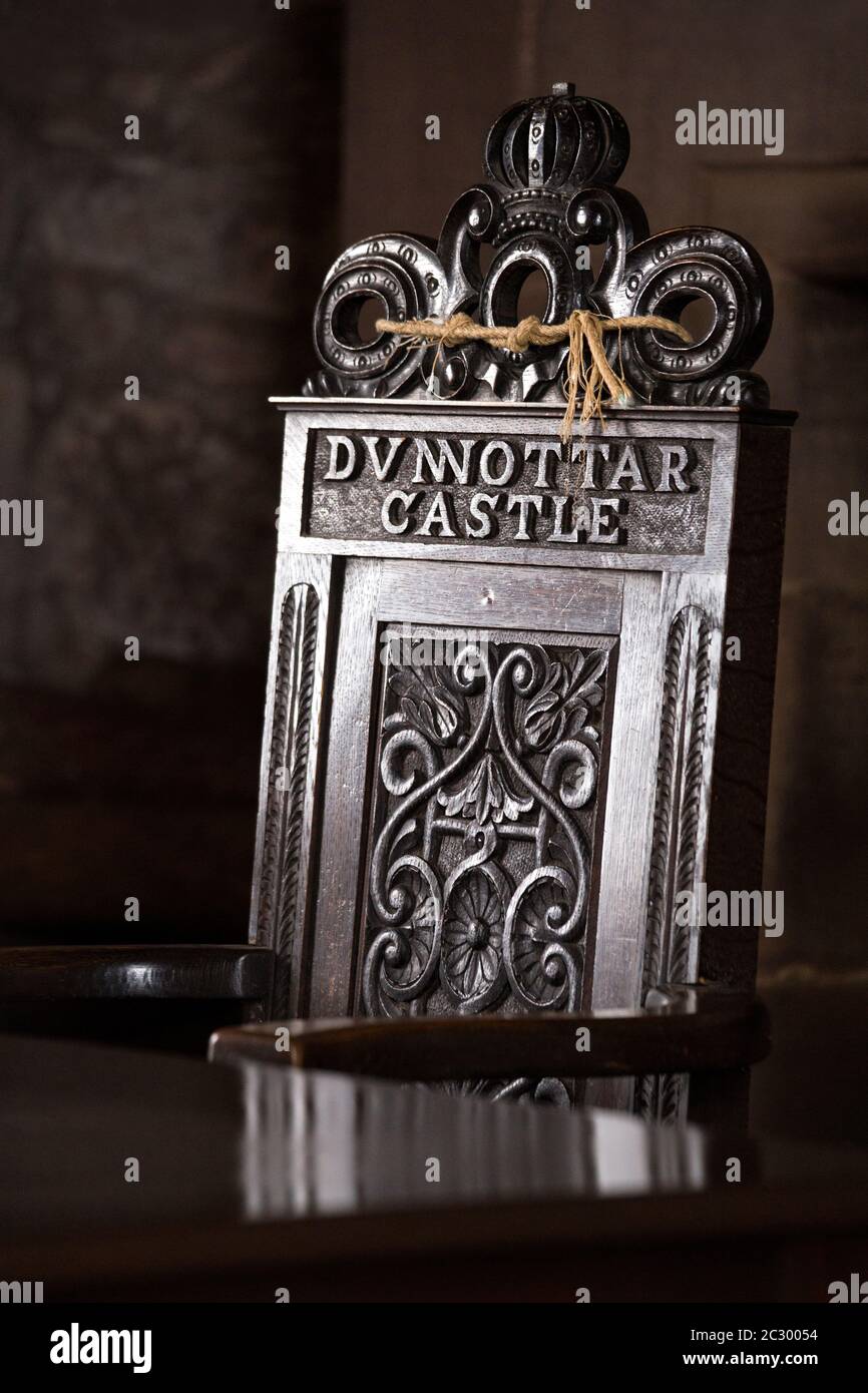 Silla de madera ornamentada con tallas de flores y pergamino y una corona en lo alto del trono con letras Dunnottar Castle, Escocia, Reino Unido Foto de stock