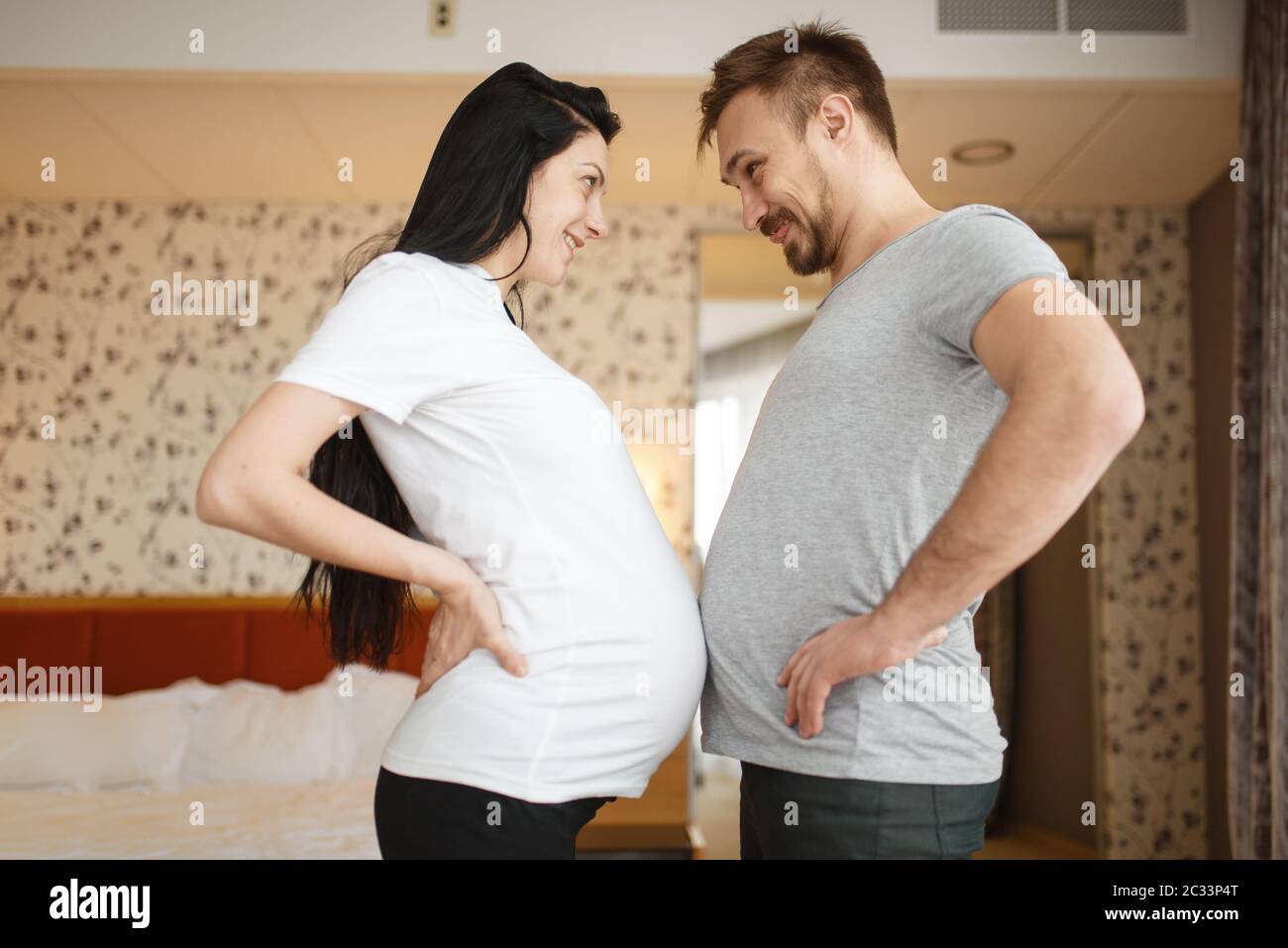 Feliz pareja, mujer embarazada con vientre en casa, dormitorio interior en  el fondo. Embarazo, período prenatal. Mamá y papá expectantes están  descansando en el sofá Fotografía de stock - Alamy