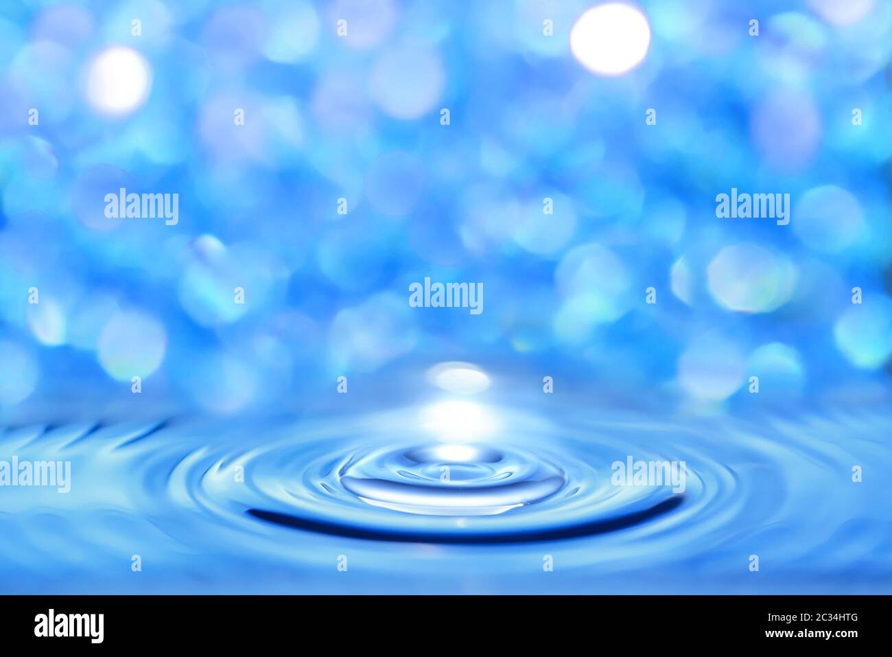 Líquido azul de agua atravesado por una onda circular sobre un fondo bokeh brillante. Foto de stock