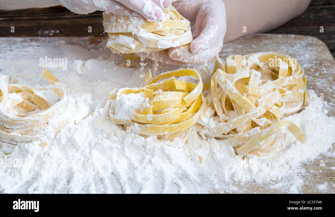 Varias pastas largas retorcidas hechas de harina de trigo duro, primer plano de alimentos sólidos crudos en una tabla de corte Foto de stock