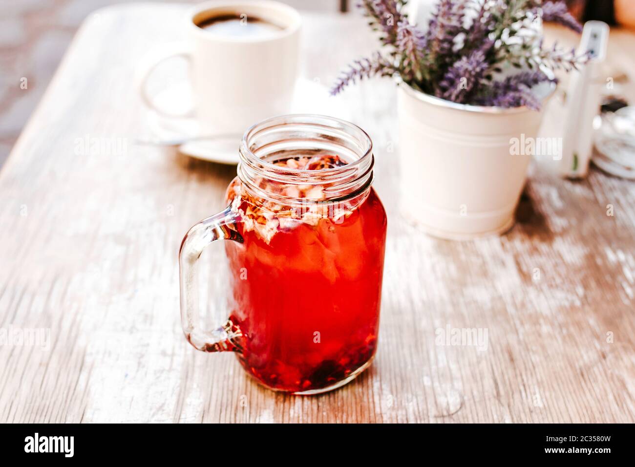 Tisana o té de hierbas rojas en un frasco transparente de cristal en una mesa al aire libre en una casa de té en la calle Foto de stock