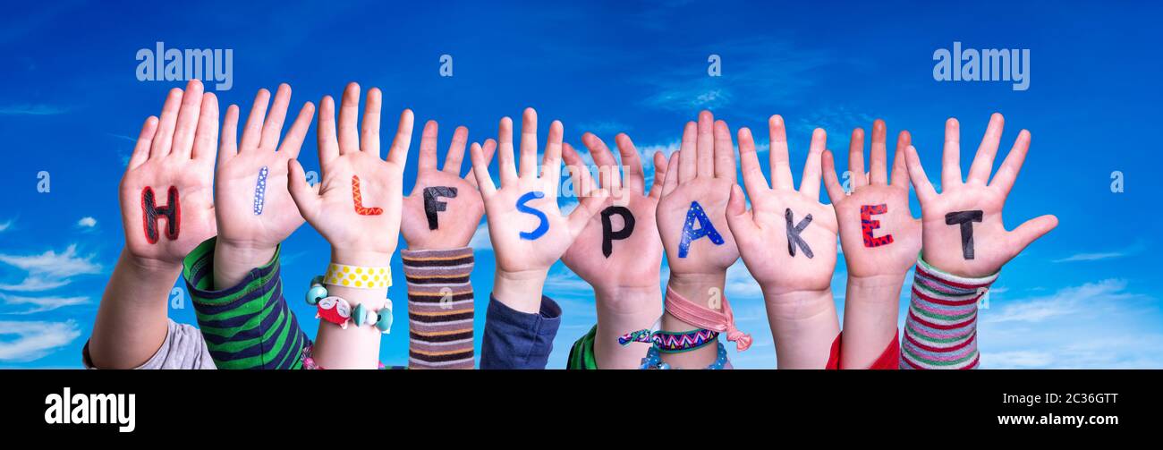 Niños edificio de manos Colorful German Word Hilfspaket significa paquete de ayuda. Cielo azul como fondo Foto de stock