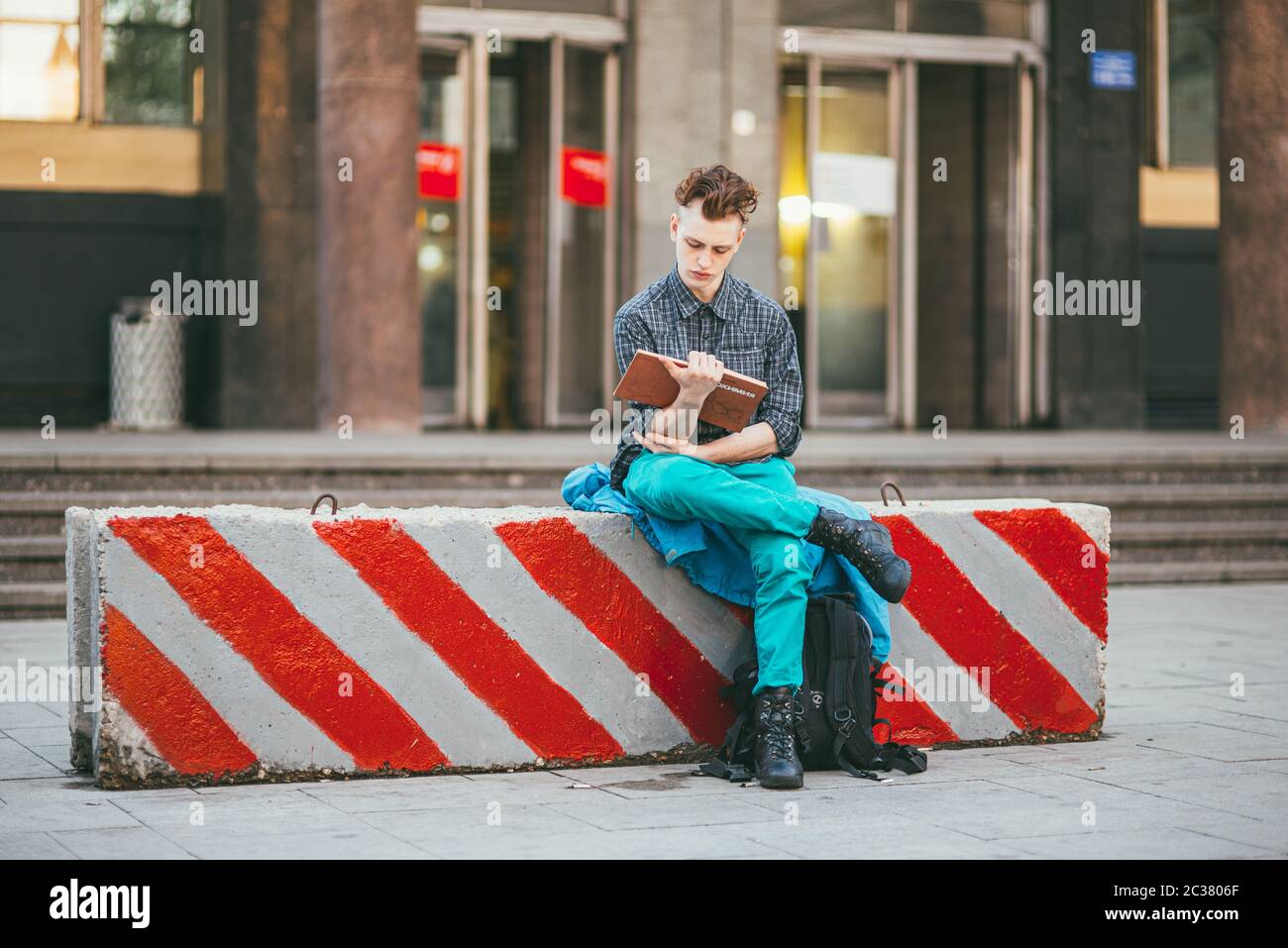 Moscú, Rusia - 25 de mayo de 2017. Un joven en una camisa gris a cuadros,  pantalones verdes y zapatos marrones se sienta en un bloque de concreto  dolor Fotografía de stock - Alamy