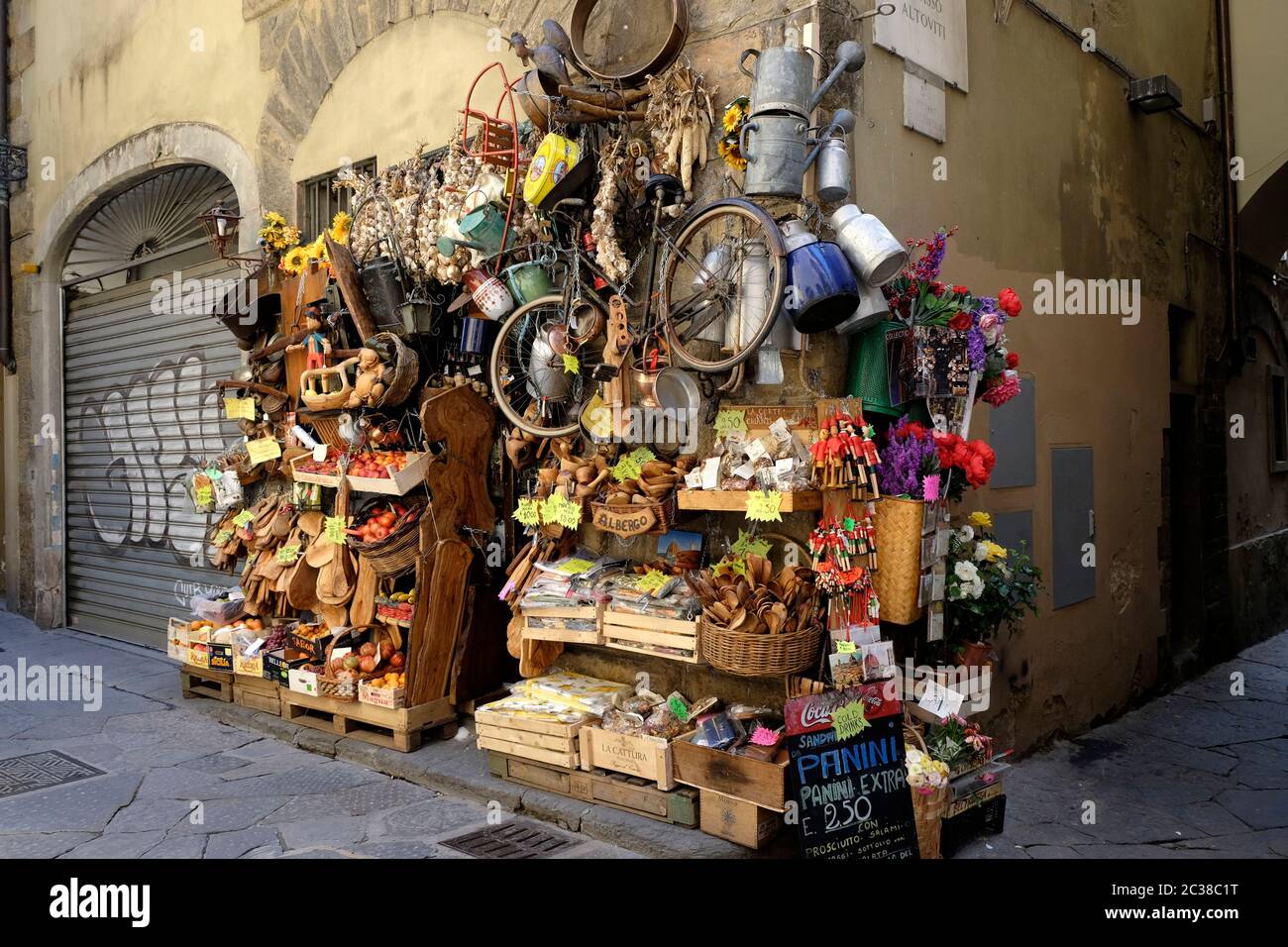 Tienda con mucho carácter que muestra frutas, verduras y artesanías en una calle lateral de Florencia cerca del Arno. Foto de stock