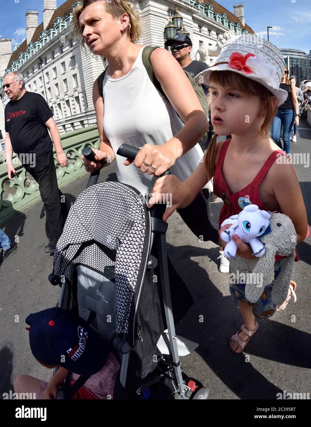 Londres, Inglaterra, Reino Unido. Niña con su madre llevando juguetes blandos, Westminster Bridge [sin modelo] Foto de stock