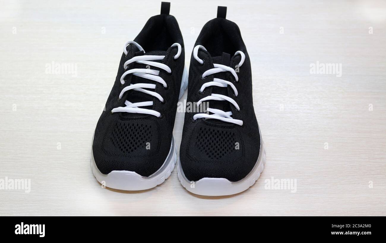 zapatillas de lona negras con cordones blancos desatados sobre un fondo  negro Fotografía de stock - Alamy