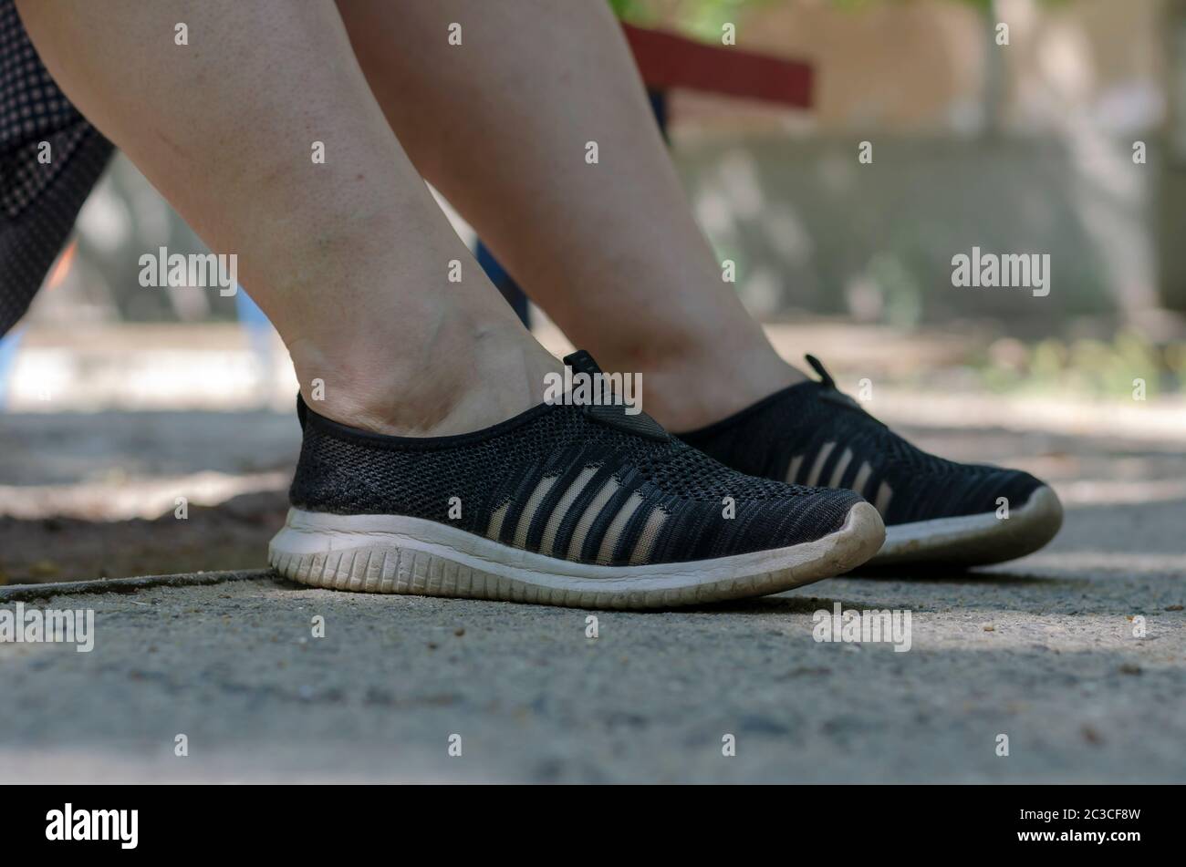 Piernas en zapatillas de deporte de una mujer descansando en un banco de  calle. Primer plano de sneakers de malla en color negro. Mujer de 30-40  años. Descanse durante el paseo de