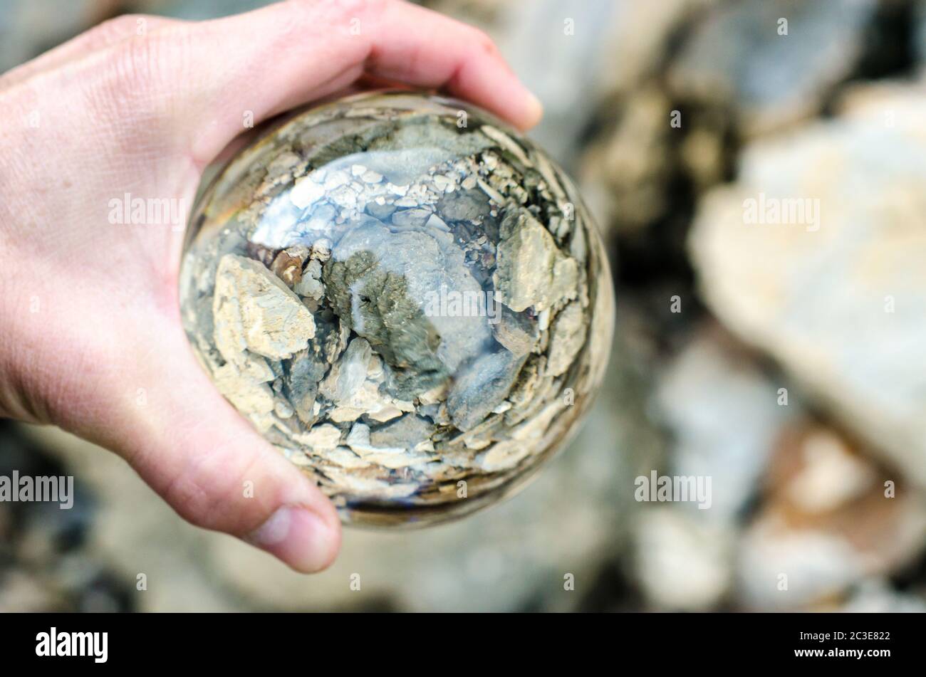 mano masculina sosteniendo una lente de bola de cristal Foto de stock