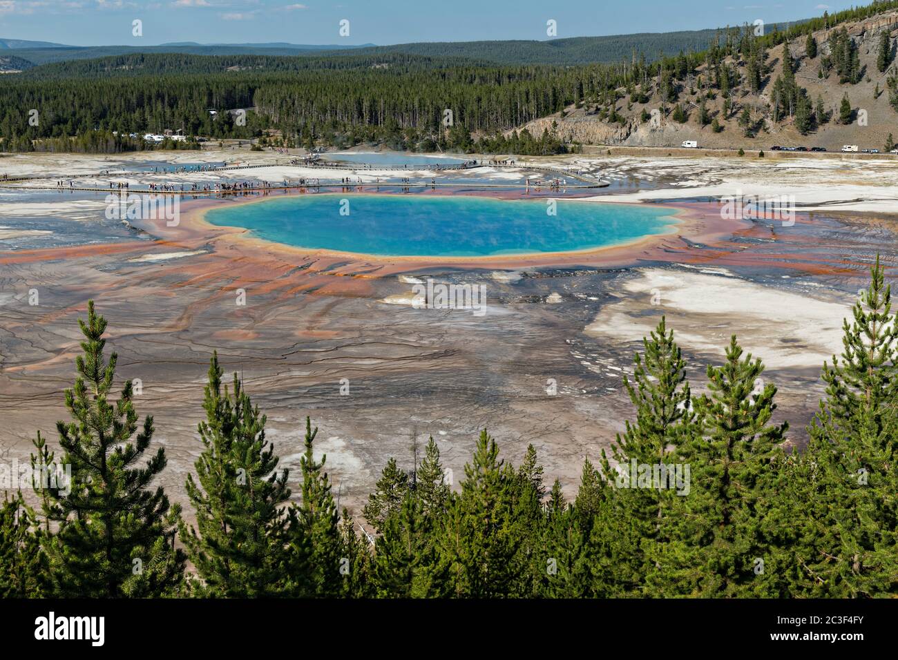 Grand Prismatic Spring la mayor fuente termal del Parque Nacional Yellowstone y la tercera más grande del mundo. Grand Prismatic tiene aproximadamente 250 por 300 pies de tamaño, un promedio de 160 grados Fahrenheit y tiene hasta 160 pies de profundidad. Los colores brillantes alrededor de la primavera son de esteras de cianobacterias. El Grand Prismatic Spring es parte del Grupo Midway Geyser Basin Excelsior en Yellowstone, Wyoming. El Geyser Excelsior se puede ver detrás. Foto de stock