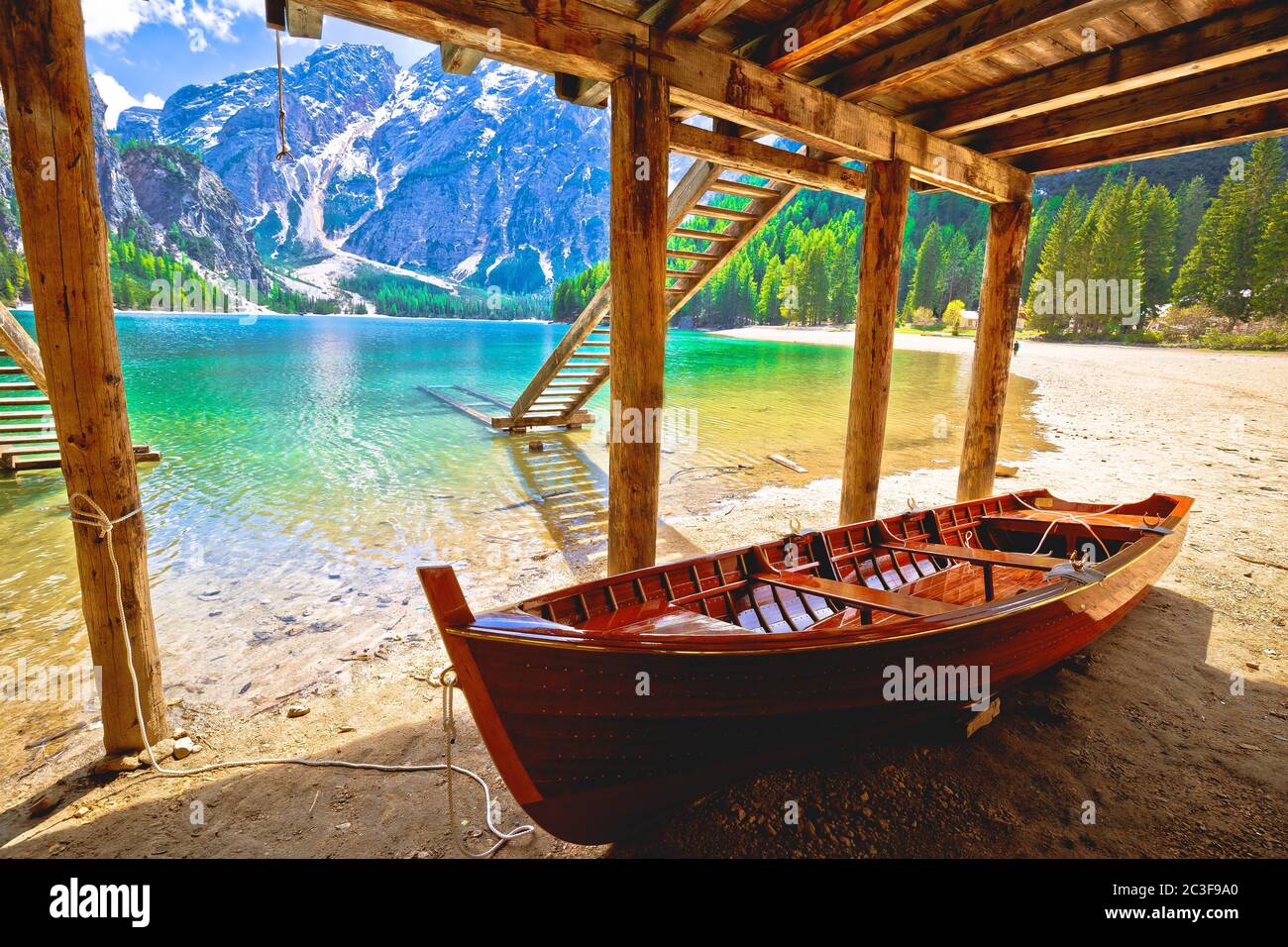 Barco de madera bajo casa de barcos en el lago Braies en el paisaje alpino Foto de stock