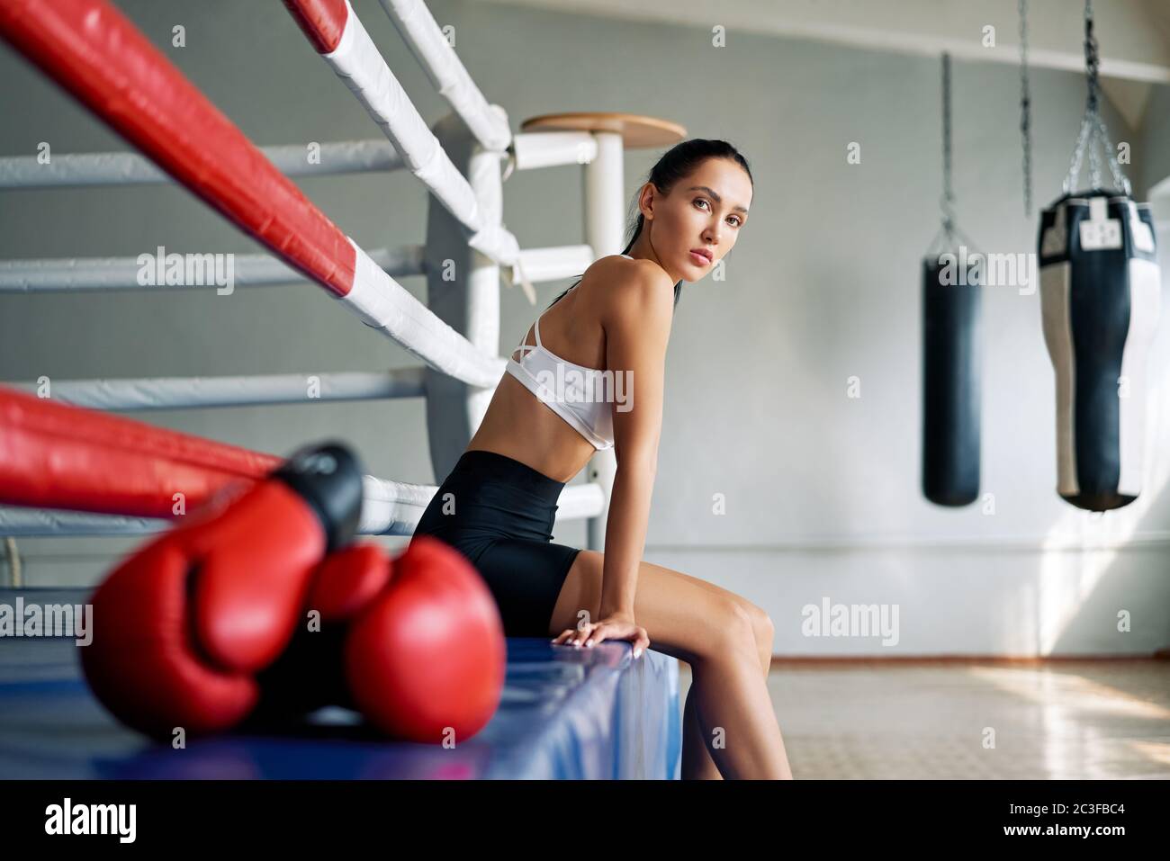 Joven hermosa mujer relajarse después de luchar o hacer ejercicio en el anillo de boxeo Foto de stock