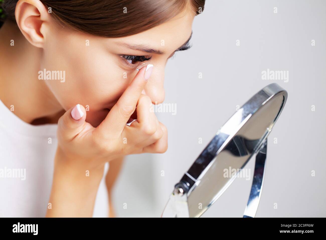 La mujer se pone lentes de contacto para la visión en casa frente a un  espejo Fotografía de stock - Alamy