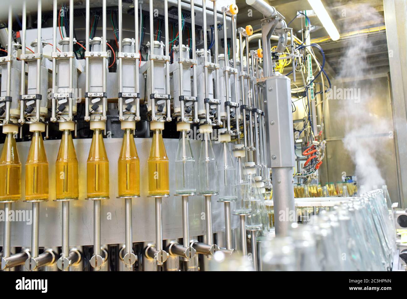 jugo de manzana en botellas de vidrio en una fábrica para la industria alimentaria - embotellado y transporte Foto de stock