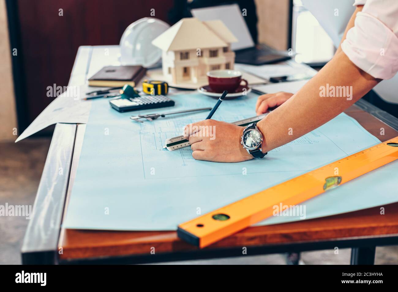 ingenieros que sostienen un bolígrafo que señala un edificio y el diseño de un plan de construcción de la instalación como guía para los constructores con detalles Foto de stock