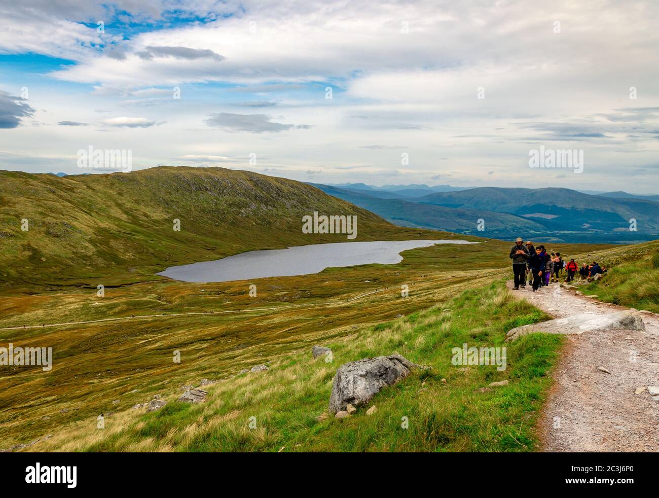 Ben Nevis / Reino Unido - Agosto 24 2019: La gente camina sobre Ben Nevis en las tierras altas de Escocia con el lago Lochan Meall una t-Suidhe en el fondo. Foto de stock