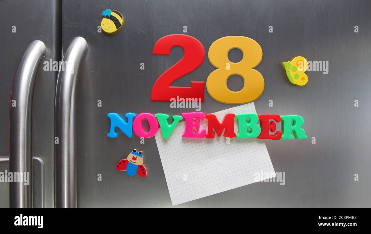 Fecha del calendario de noviembre de 28 hecha con letras magnéticas de plástico que contienen una nota de papel gráfico en la puerta del refrigerador Foto de stock