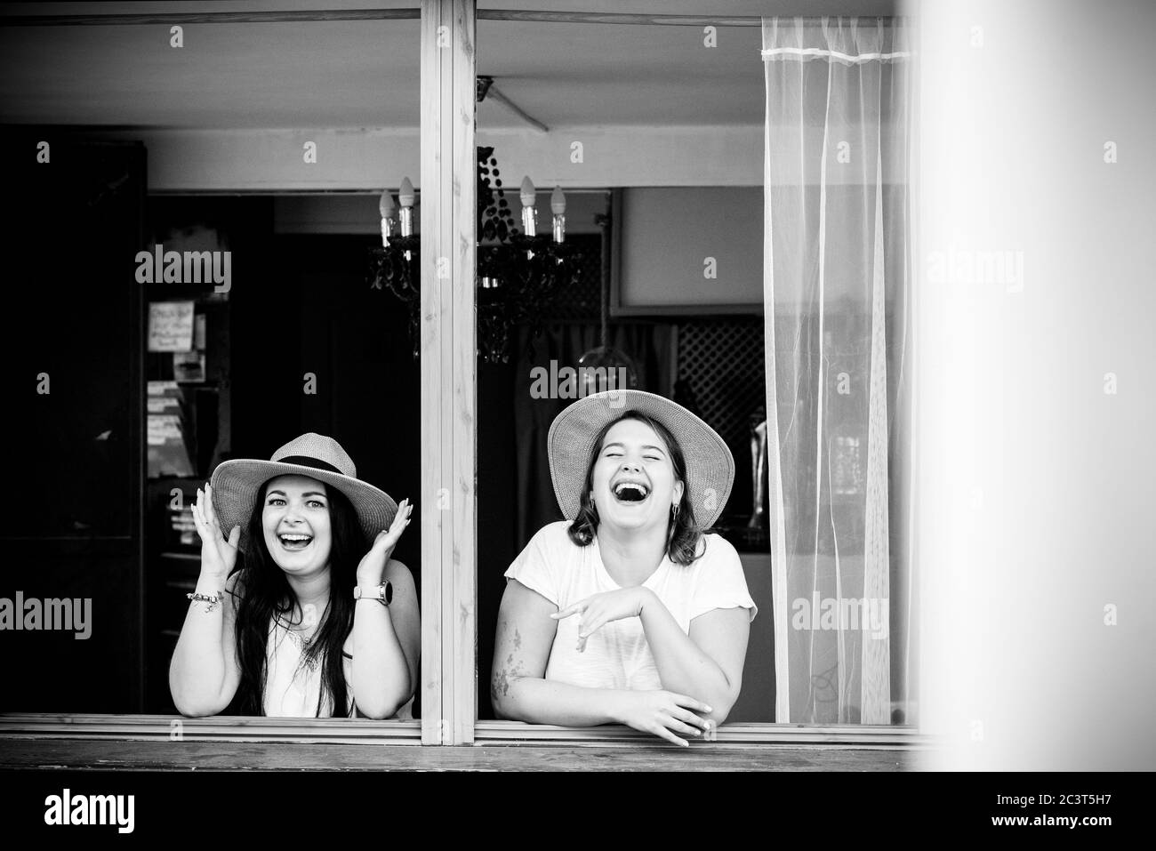 Feliz pareja joven de amigas disfrutar de la amistad y reír mucho juntos en la ventana - la gente y divertido concepto de vida Foto de stock