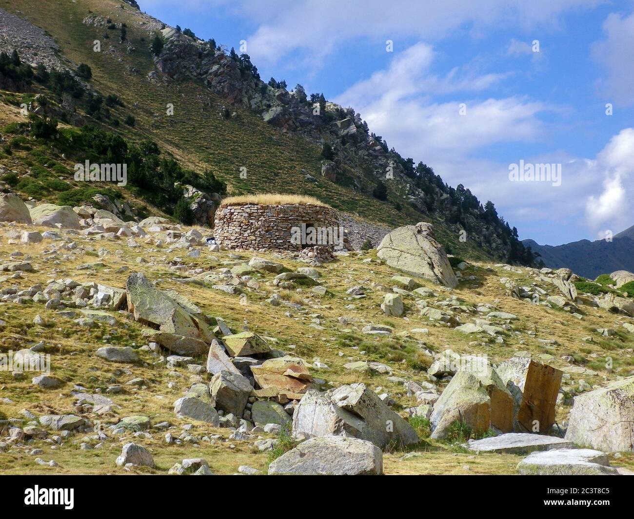 Paisaje de refugio de alta montaña en medio del valle con árboles y piedras a su alrededor Foto de stock