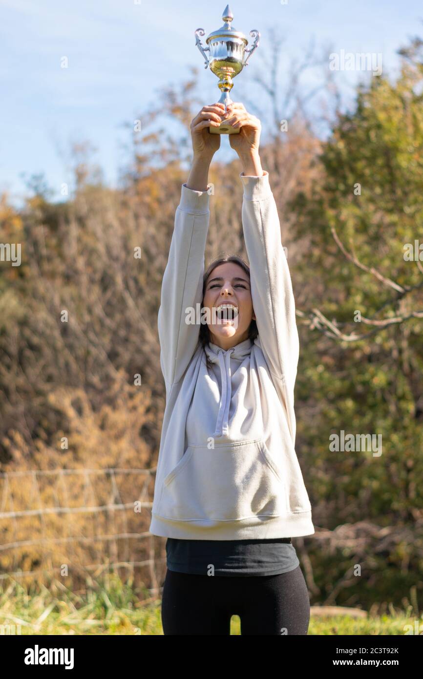 Una joven muy feliz lleva un trofeo al aire libre en un parque. Ella está  usando una sudadera ligera y tiene un largo cabello marrón Fotografía de  stock - Alamy