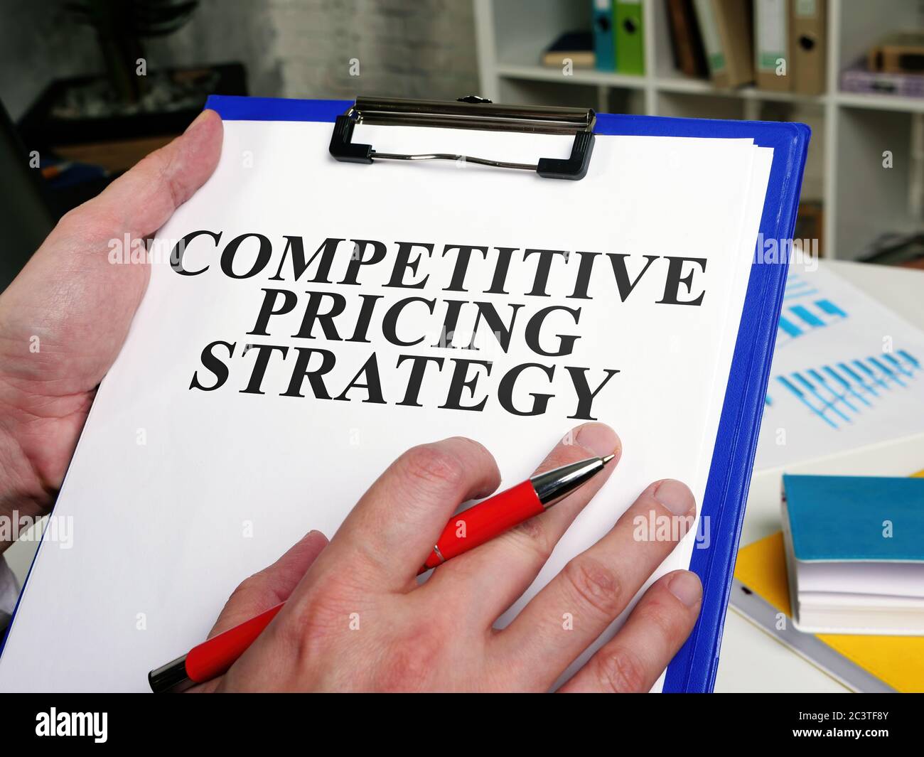 Un empresario lee un informe de estrategia de precios competitivos. Foto de stock