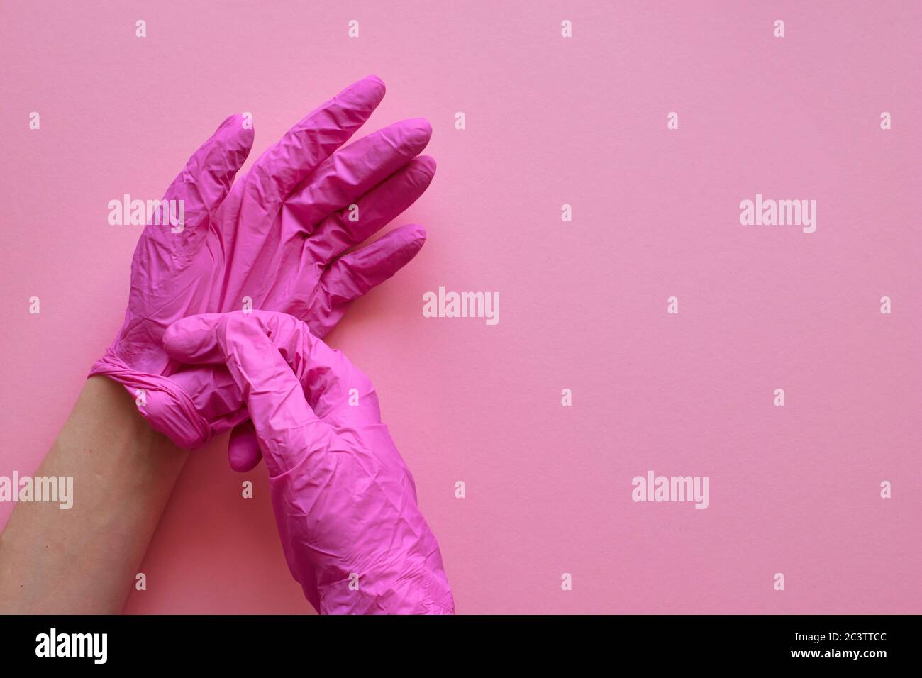 Manos con guantes rosas sobre fondo rosa. Concepto de prevención del virus coronavirus covid-19. Fondo rosa, copyspase. Diseño, vista superior, plano. Foto de stock