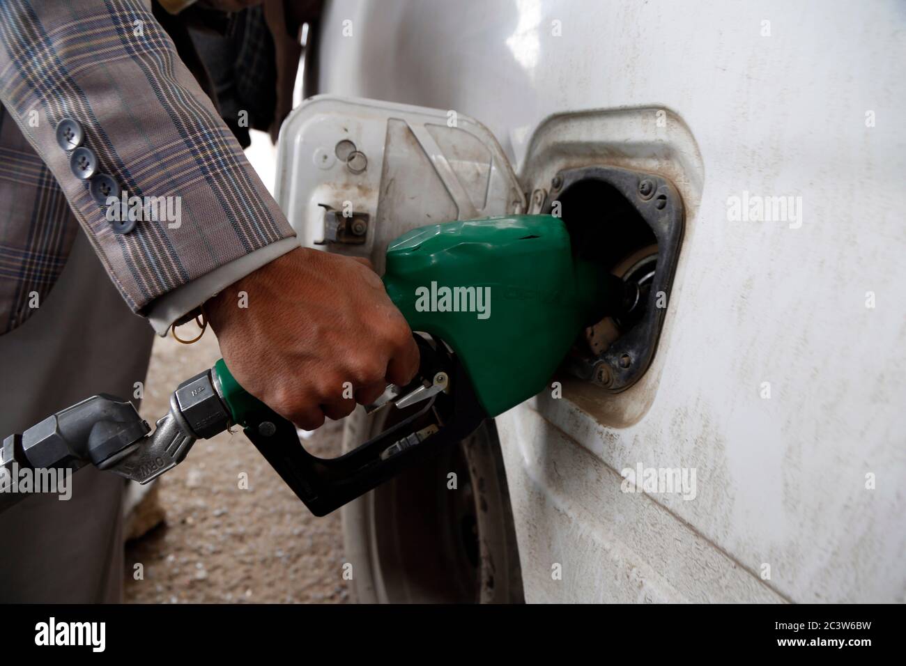 Sanaa. 22 de junio de 2020. Un trabajador rellena un coche en una gasolinera en medio de una grave escasez de combustible en Sanaa, Yemen, el 22 de junio de 2020. La mayoría de las estaciones de combustible en Sanaa, capital de los hutíes yemenitas, se secaron el domingo después de una escasez de combustible de dos semanas en toda la ciudad, dijeron las autoridades locales y los residentes. Solo algunas bombas de combustible suministran gasolina y diésel a los vehículos que se alinean en largas colas. Crédito: Xinhua/Alamy Live News Foto de stock