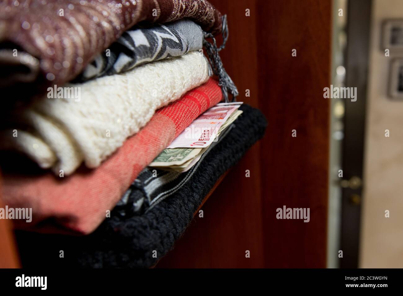 Euros y dólares salidos de un montón de ropa en un armario Foto de stock