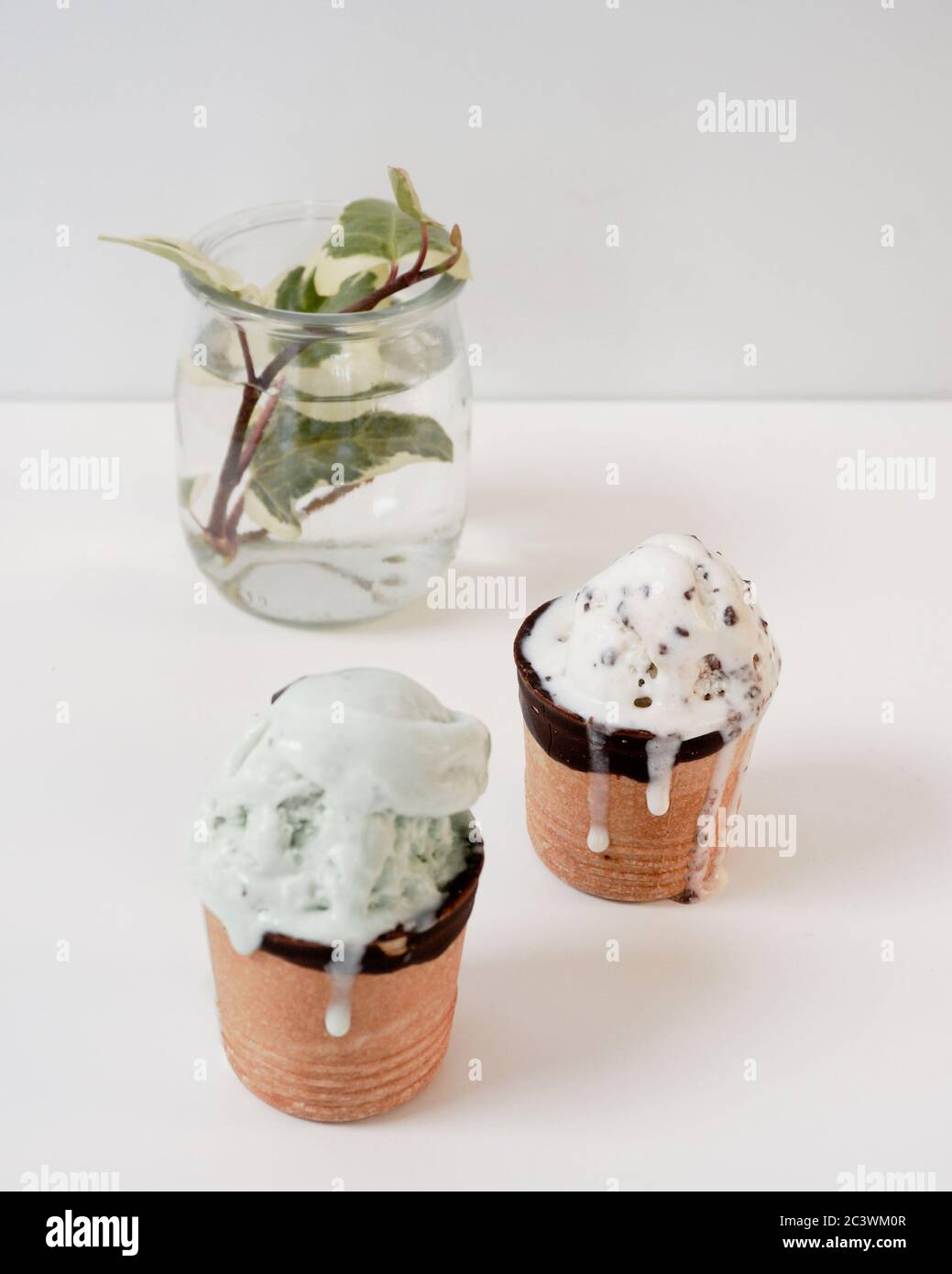 Fundición artesanal menta y vainilla sabor helado en tazas de gofres glaseado con chocolate verde offset en botella de vidrio sobre fondo. Foto de alta calidad Foto de stock