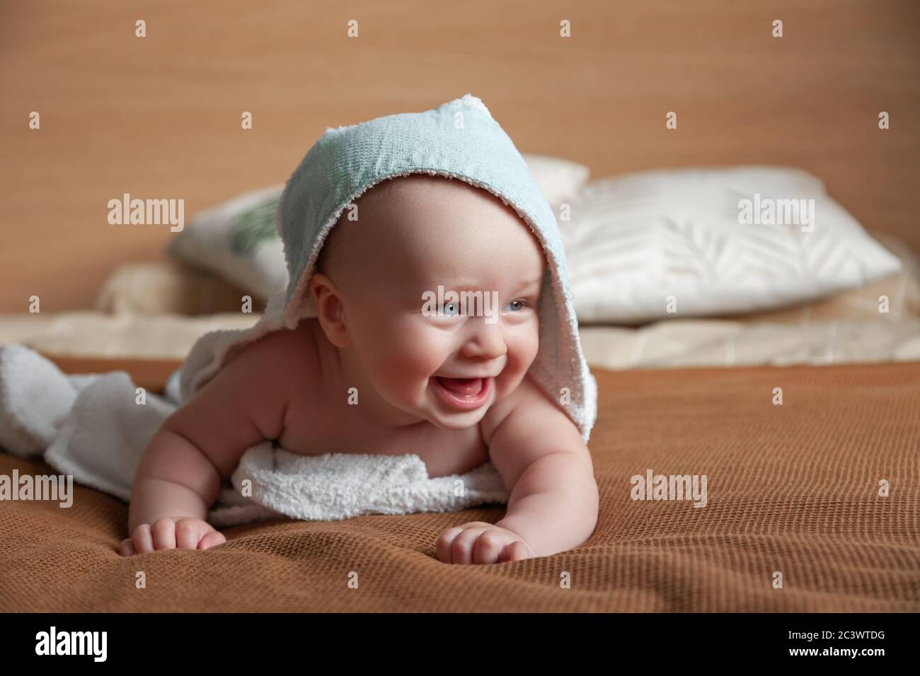 ute pequeño bebé yace en la cama envuelta en una toalla blanca con capucha Foto de stock