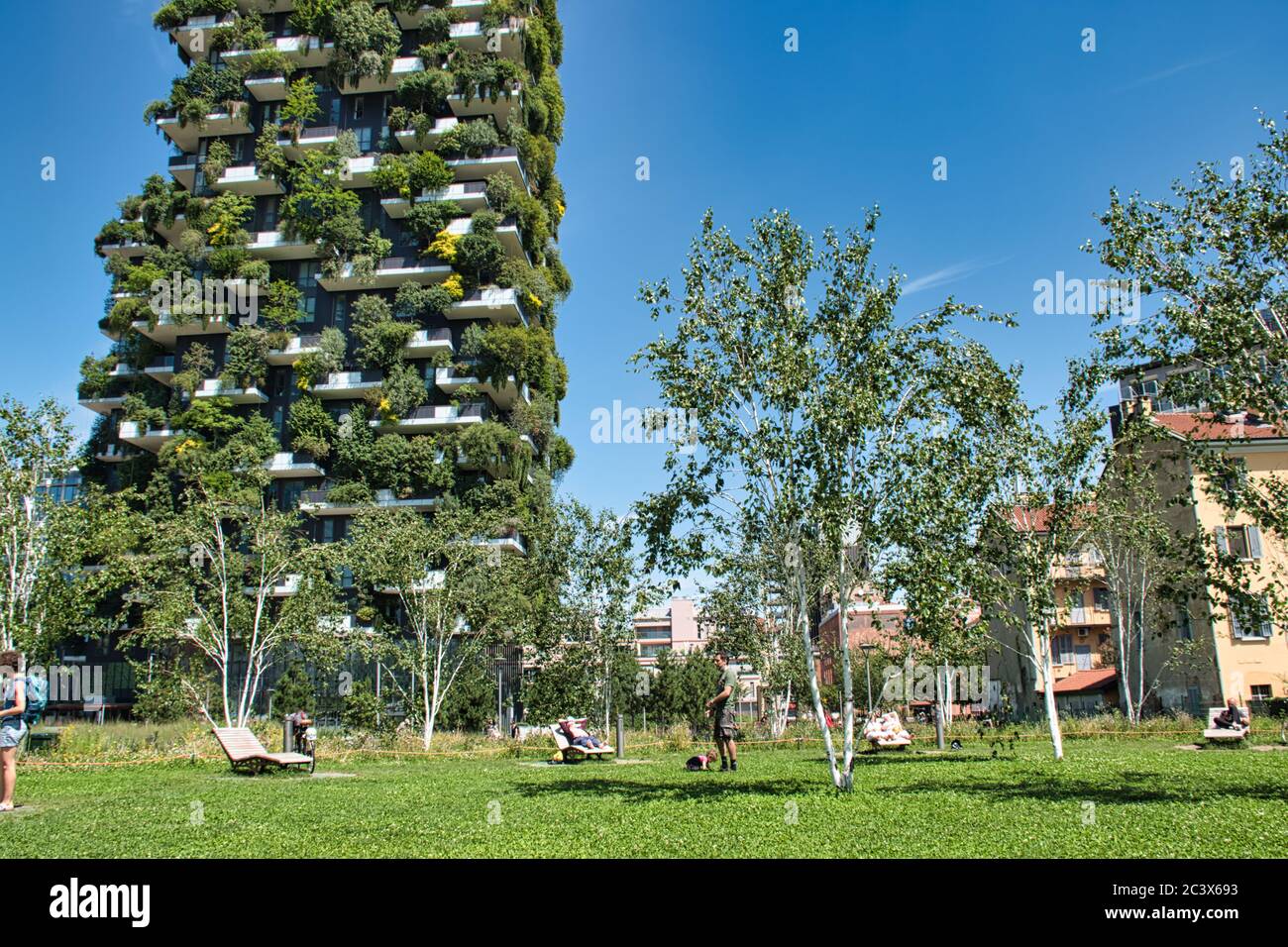 Milán, Italia 06.20.2020: Gente disfrutando del sol en hamacas separadas en el nuevo parque de la Biblioteca de árboles frente al Bosco Verticale, Fores vertical Foto de stock