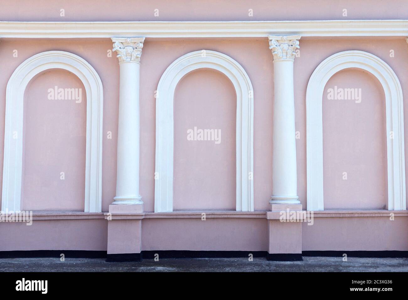 Fachada rosa sin ventanas del edificio con columnas blancas y arcos. Hermoso exterior. Fondo, fondo de pantalla Foto de stock