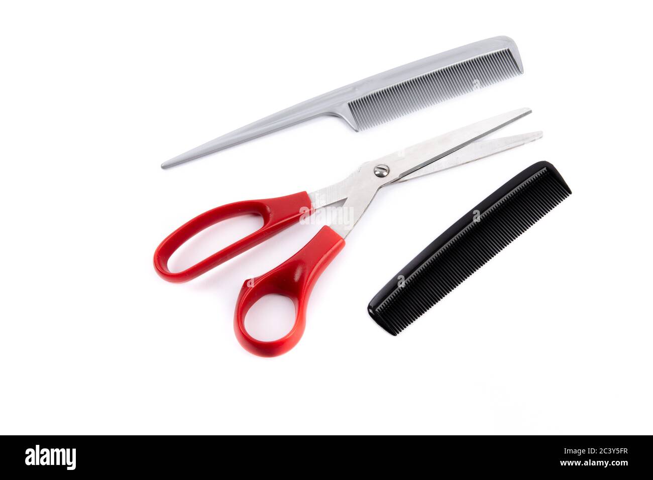 herramientas de corte de pelo, incluidas tijeras de mango rojo y dos peines aislados en blanco Foto de stock
