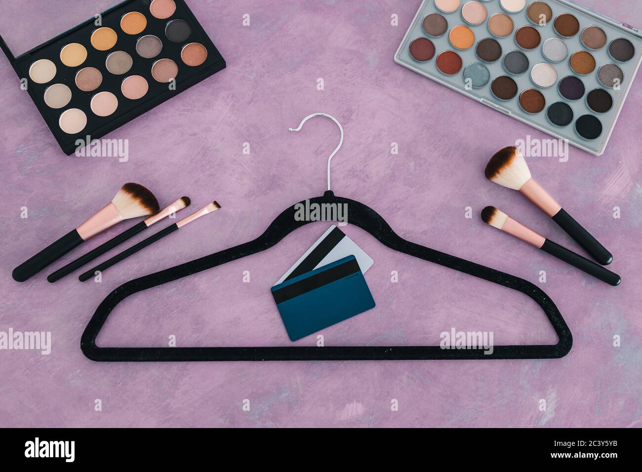 industria de la belleza y concepto de compras, escritorio rosa con cosméticos y accesorios de moda en ella, incluyendo percha de ropa y tarjetas de crédito Foto de stock