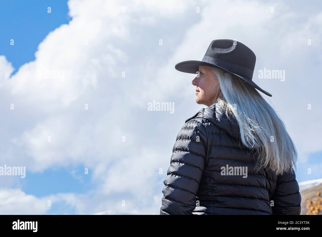 Retrato de la mujer mayor con sombrero contra el cielo azul y. nubes Foto de stock