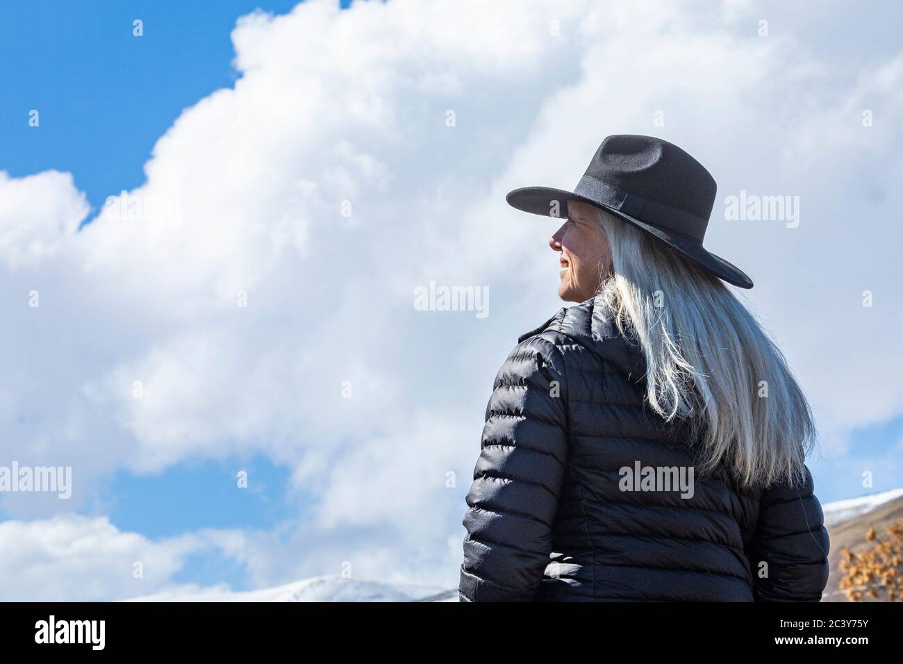 Retrato de la mujer mayor con sombrero contra el cielo azul y. nubes Foto de stock