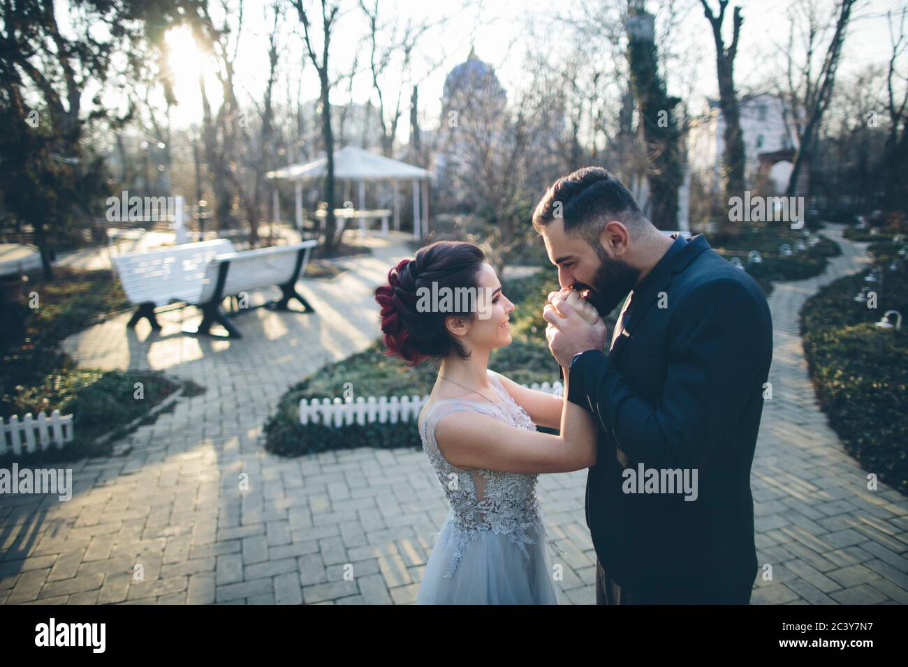 Novio besando las manos de su esposa recién casada en el jardín Foto de stock