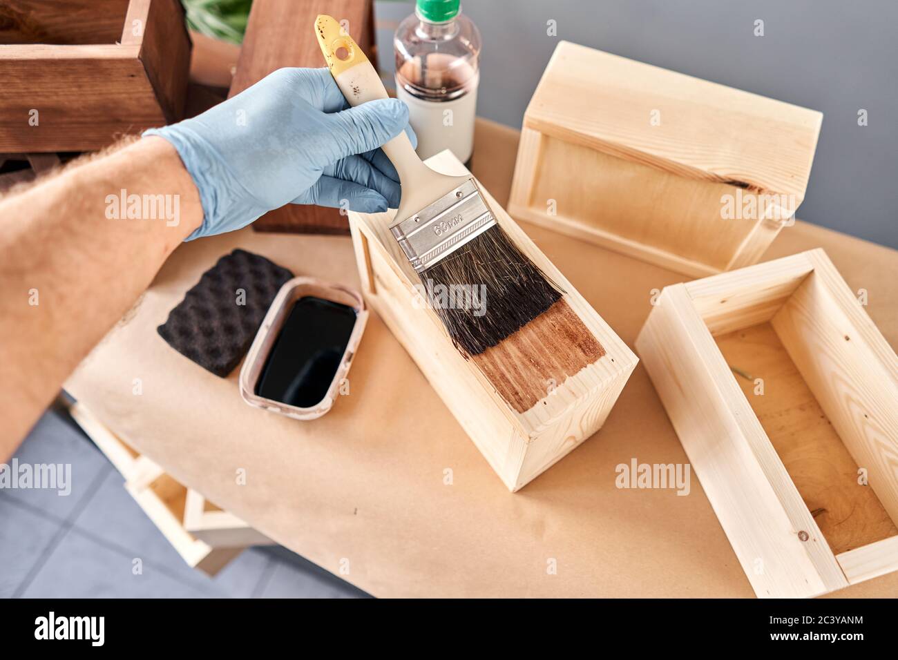Hombre carpintero barnizar caja de madera para flores con cepillo en su  taller de trabajo en madera de pequeña empresa. En su trabajo, ¿utiliza  manchas o madera Fotografía de stock - Alamy