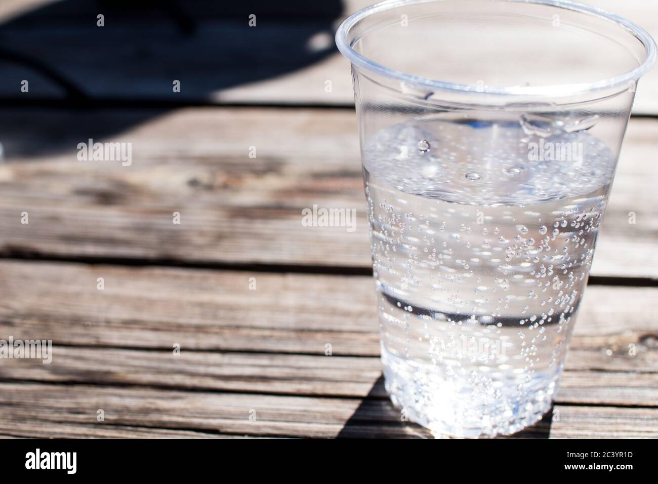un vaso de agua con agua brillante está en una mesa de madera con pequeñas  burbujas que salen desde el fondo Fotografía de stock - Alamy