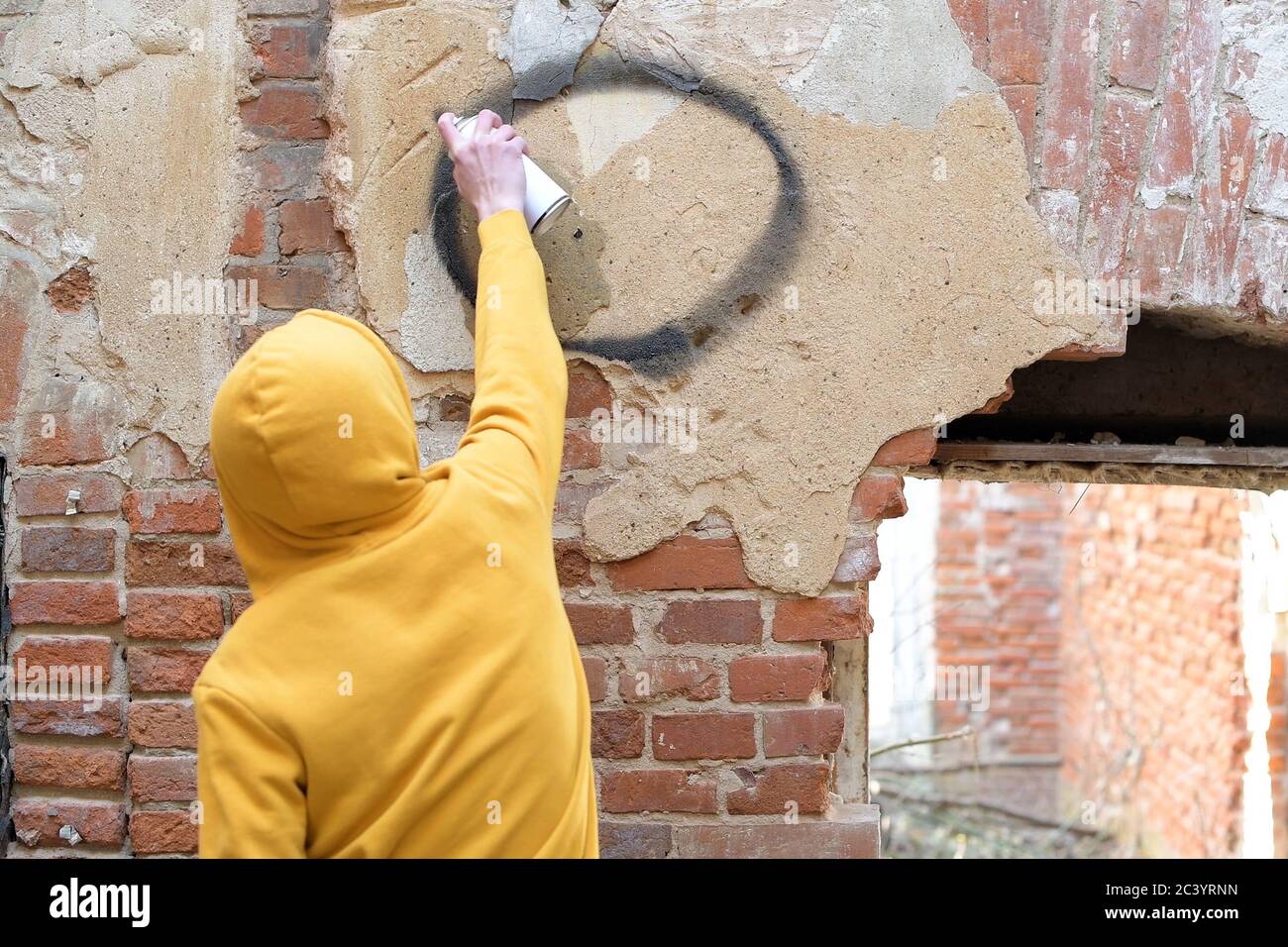 Un adolescente dibuja en una pared de un edificio abandonado una lata de pintura en aerosol Foto de stock