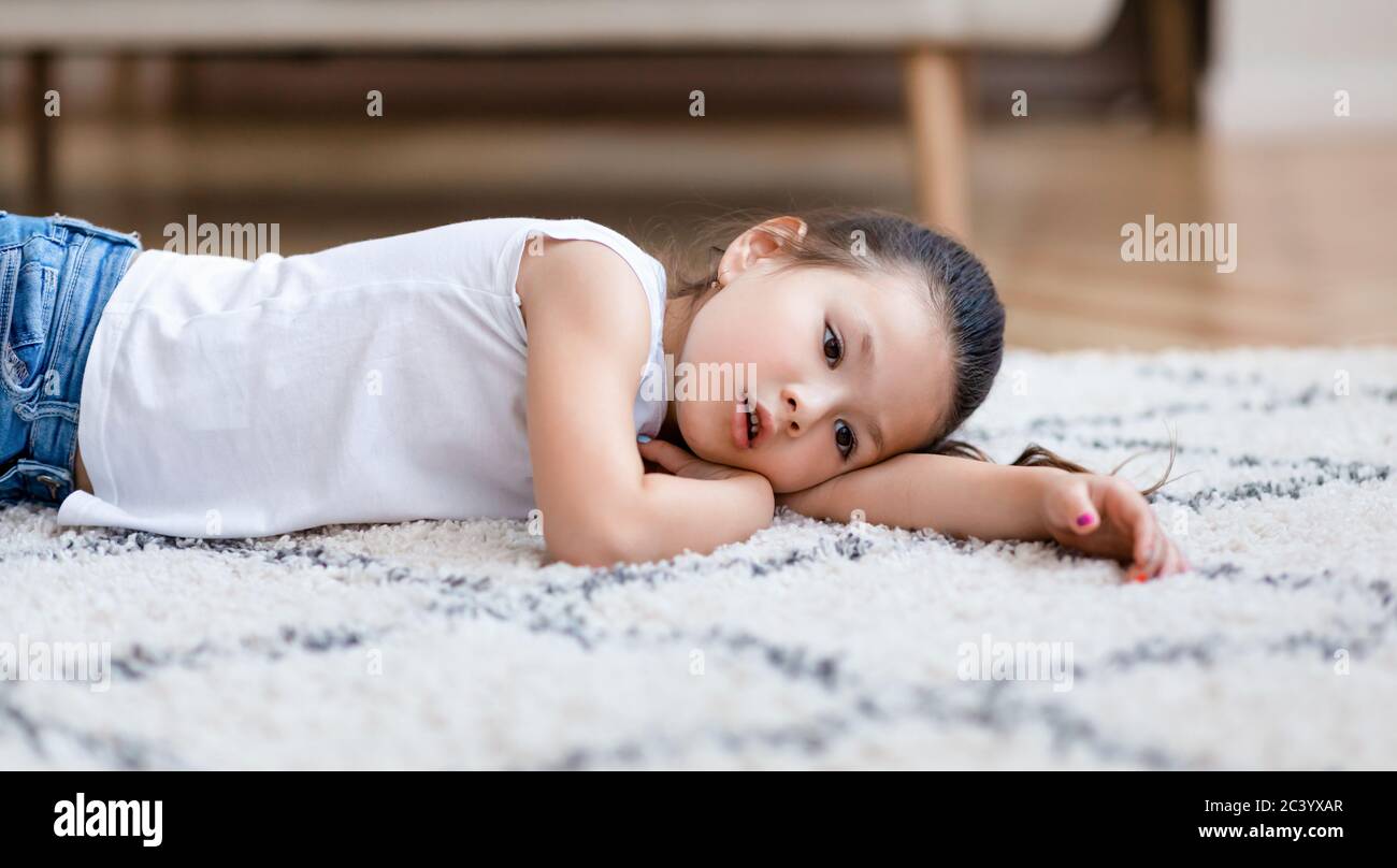 Aburrimiento. Aburrido asiático Lying en el suelo en casa, Panorama Foto de stock